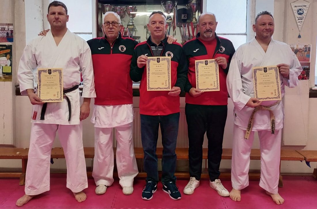 New Dan grades holding their certificates with senior instructors in club tracksuits
